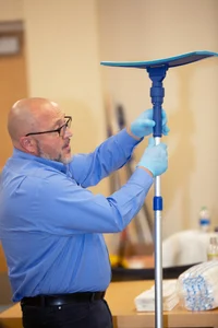 man in light blue button shirt holding a mop