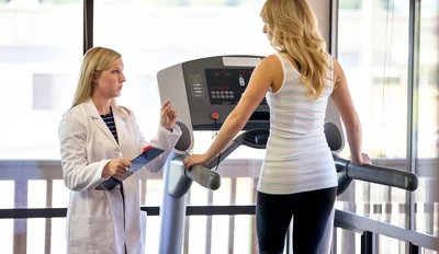 fit woman on treadmill speaking with trainer