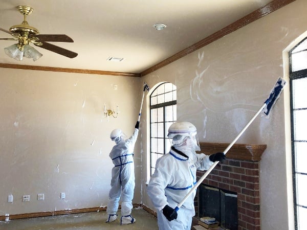 two men in hazmat suits suing Premira & CAD Restoration in rooom