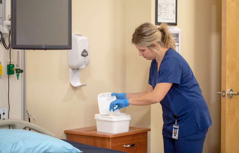 nurse in navy scrubs grabbing cleaning wipes