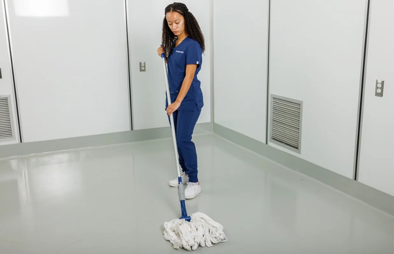 nurse in navy scrubs mopping floor
