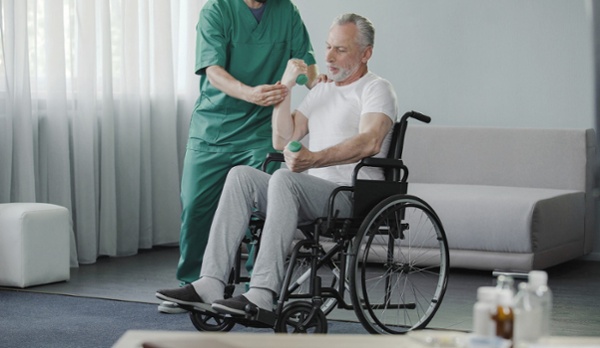 man in wheel chair doing long-term-care-senior-rehab with physical therapist