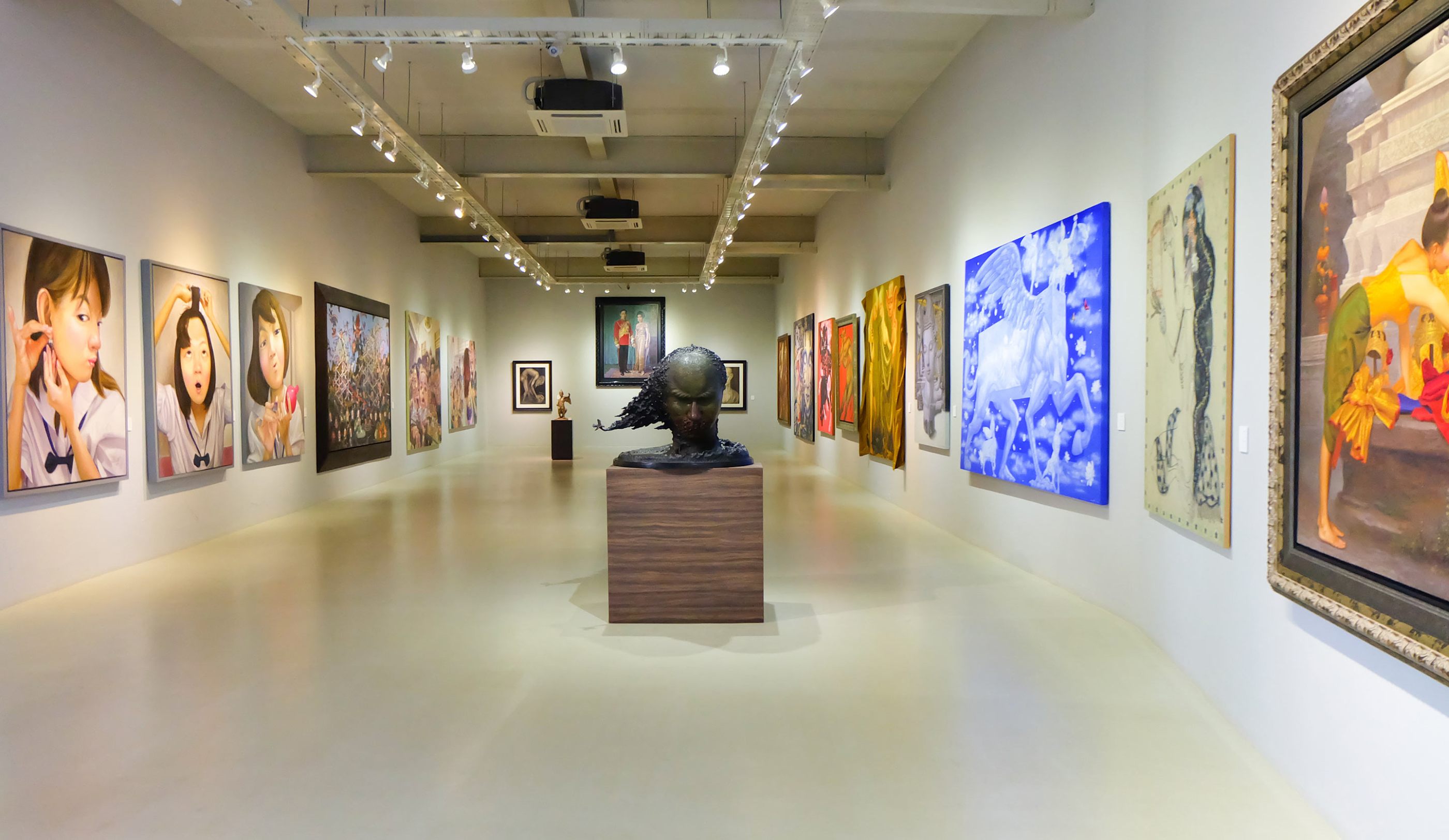 A wide museum hallway with paintings displayed on the walls